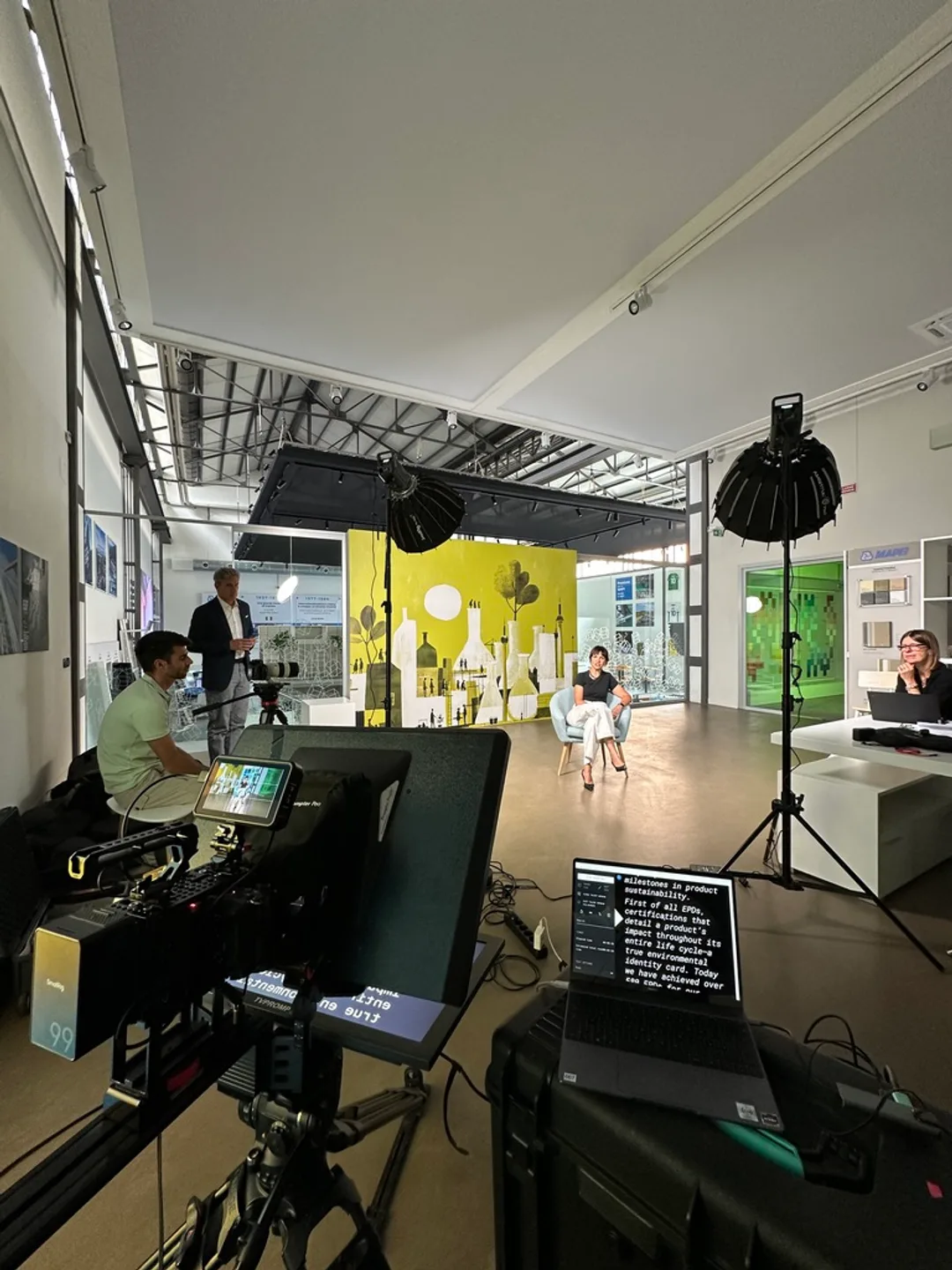 Behind the scenes: camera and teleprompter framing a single interview subject on set