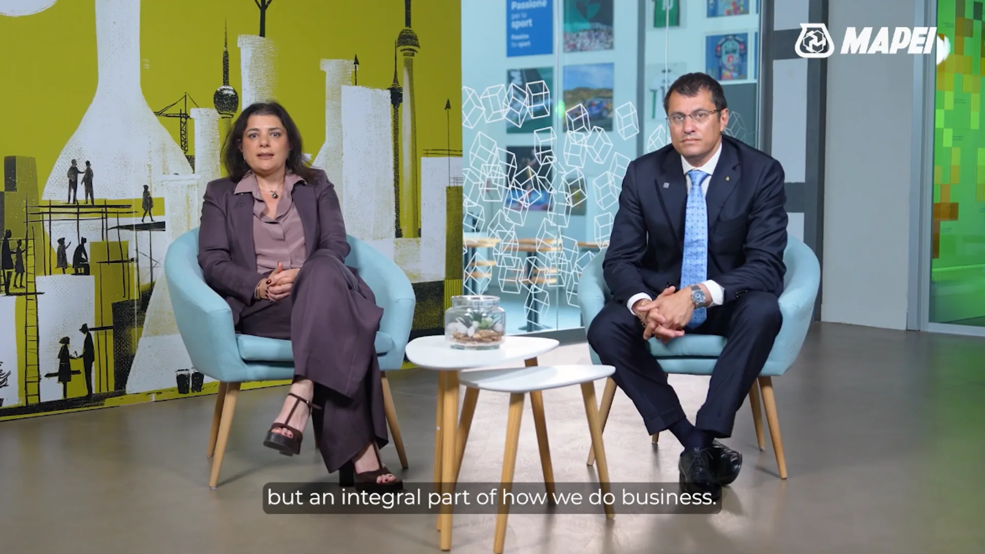 Two Mapei executives seated for a corporate interview in front of branded set design